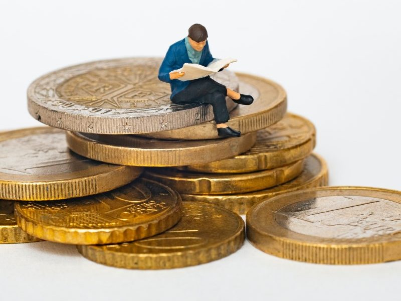 Figurine man sitting on stack of coins