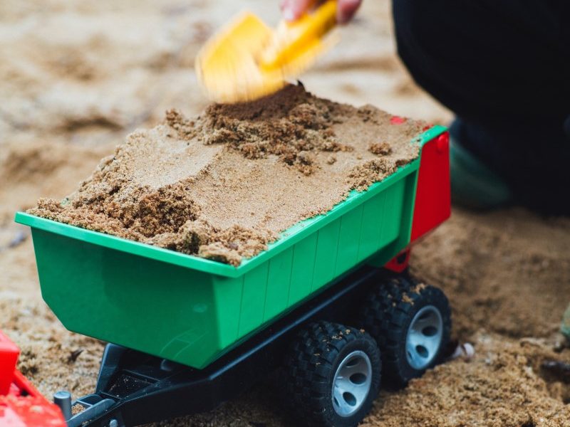 Child filling a truck with sand